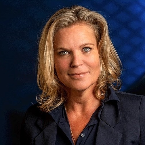 Annet Scheeren, Head of Sustainable Employability bij Rabobank, met blond schouderlang haar en een donkerblauw jasje, voor een donkerblauwe achtergrond.